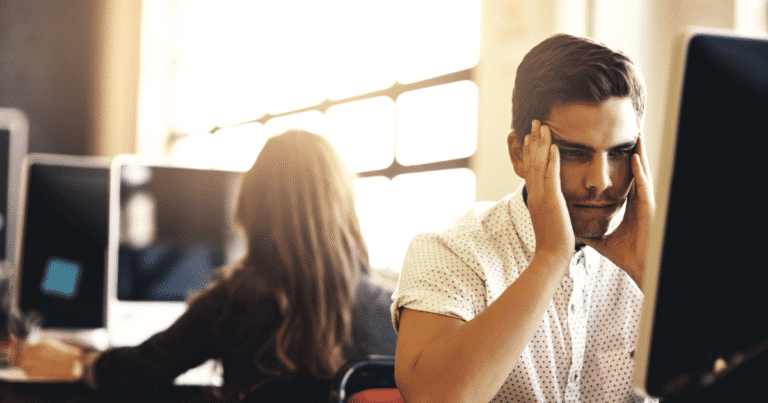 Hombre con las manos en la cabeza frustrado por WordPress lento en la oficina