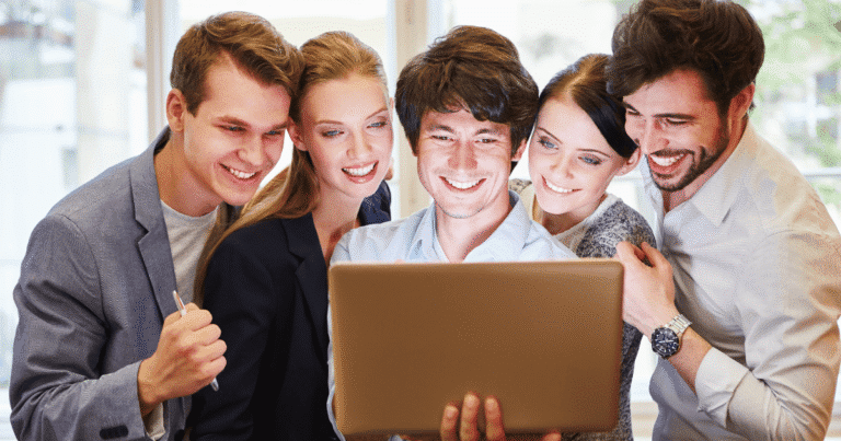Grupo de 5 personas felices celebrando la identidad digital ONG frente a un ordenador portátil.