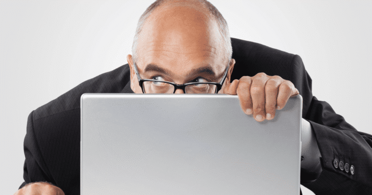 Hombre asomándose detrás de un monitor vigilando copias de seguridad web