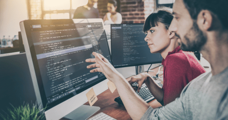 Chica y chico desarrolladores web con código en pantalla