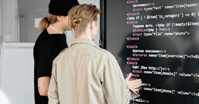 Dos programadores analizando código PHP en una pantalla gigante