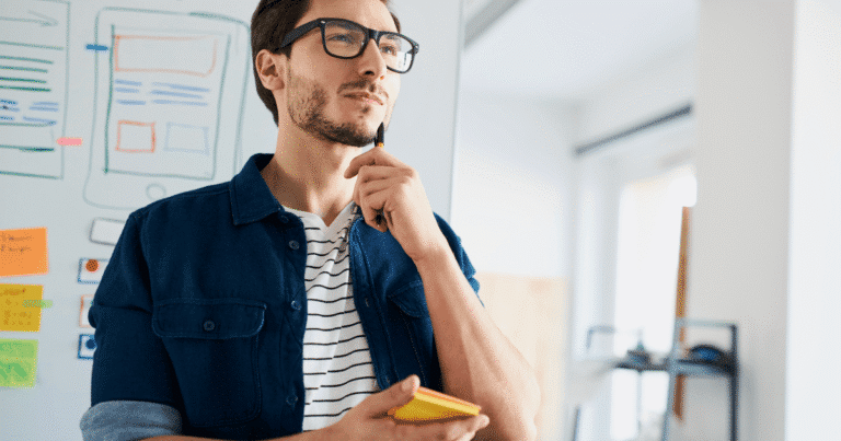 Hombre en actitud pensativa con un bloc de notas frente a una pizarra que muestra un croquis de arquitectura web, representando el diseño técnico previo de un sitio WordPress optimizado.