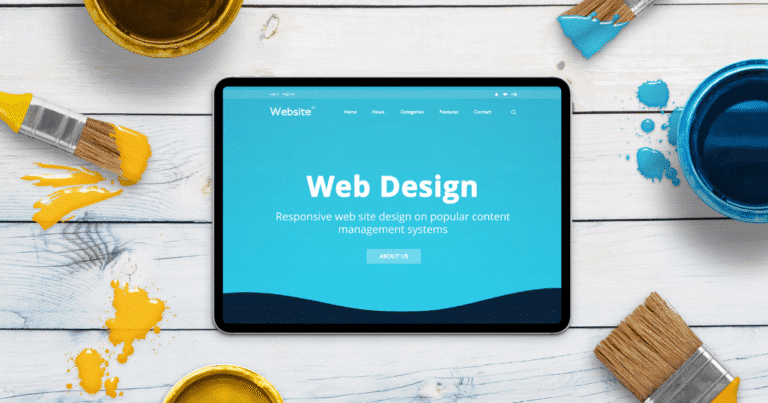 Tablet mostrando un proyecto de diseño web sobre una mesa de madera con herramientas creativas como brochas y pinturas azul y amarilla, representando la unión entre branding y optimización técnica.