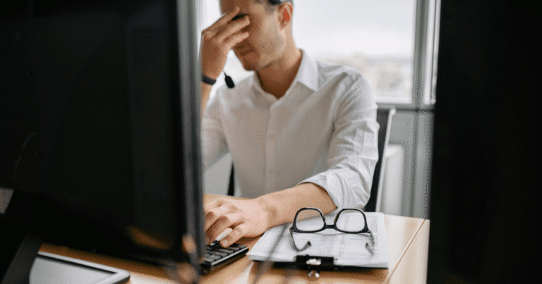 Hombre profesional con gesto de frustración frente a su ordenador por un error invisible en su página web que afecta a su negocio.