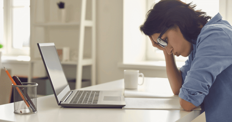 Mujer con gesto de frustración frente a un ordenador portátil en una oficina vacía por un error de servidor en su web corporativa o de ONG.